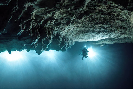 Divers adventure in suns rays in underwater caveの素材