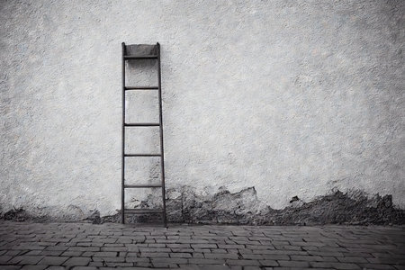 Used step ladder against wall of old house in white gray tonesの素材