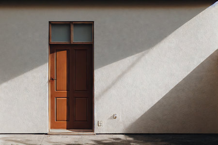 Brown wooden front door of house on smooth light gray wallの素材