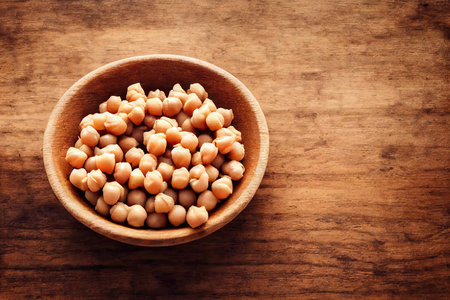 Chickpeas poured into deep clay bowl isolated on wooden backgroundの素材