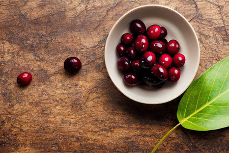 Small white bowl with fresh appetizing and healthy cranberry standing on tableの素材
