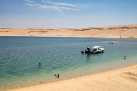 desert mirage of crystal-clear lake, with boat and sunbathing tourists visible, created with generative aiの素材