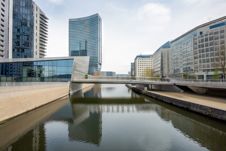 modern water channel with contemporary bridge, and cityscape in the background, created with generative aiの素材