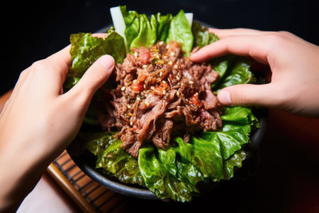 hands reaching for bulgogi wrapped in lettuce leafの素材