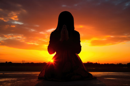 human silhouette praying against sunsetの素材