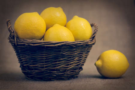 lemons in a basket on a brown backgroundの写真素材