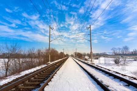 line snowy railroad tracks with blue skyの写真素材