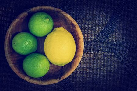 limes and lemons in a bowl on a wooden backgroundの写真素材