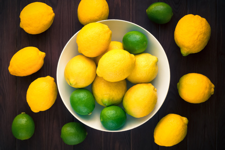 limes and lemons in a bowl on a wooden backgroundの写真素材