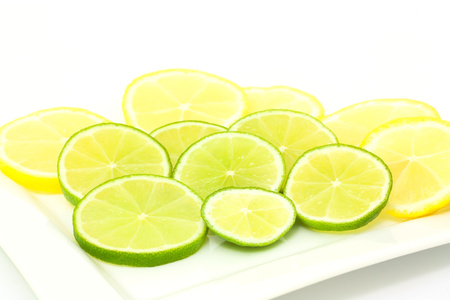 sliced limes and lenon in a white bowlの写真素材