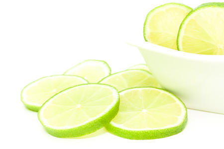sliced limes in a white bowlの写真素材