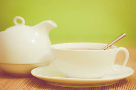 white porcelain teacup and teapot on a green backgroundの写真素材