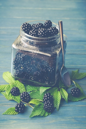 Blackberries in a glass jar with leavesの写真素材