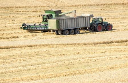 tractor and combine harvester on a wheat fieldの写真素材