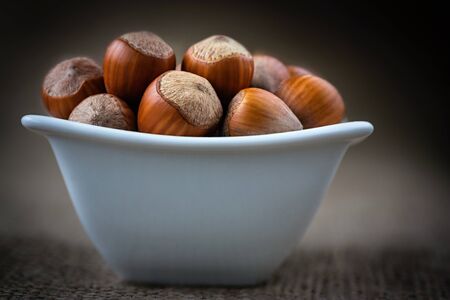 hazelnut in a white bowl on wooden backgroundの写真素材