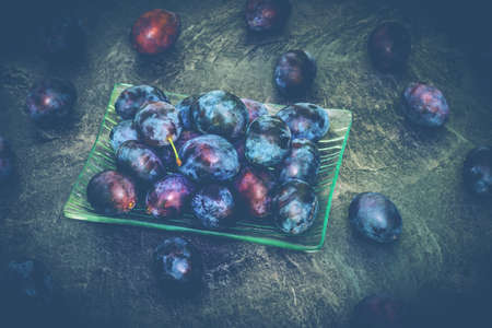 Plums in a glass bowl on a marble backgroundの写真素材