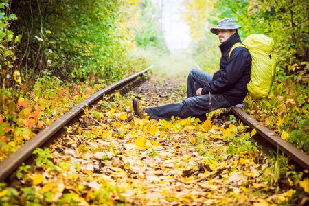 man with a backpack sitting on the railsの写真素材