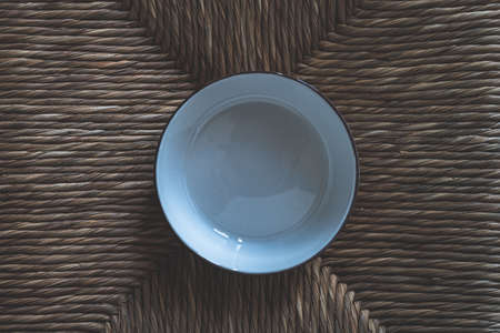 White ceramic bowl on straw chair surface.の写真素材
