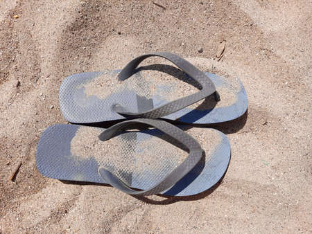 Flip flops photographed from above covered with sand on a generic beach in summer with copy space.の写真素材