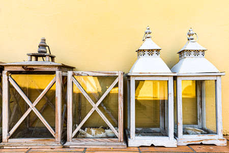 Italy. Four wooden garden lanterns placed under a yellow wall.の写真素材