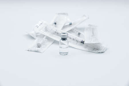Bottle of a drug or vaccine against Virus with a group of syringes still packed, isolated on white background.の写真素材