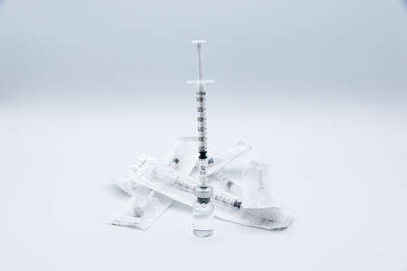 Preparing a dose of vaccine against Virus with a syringe filled on the bottle and and near a group of syringes still packed, isolated on white background.の写真素材