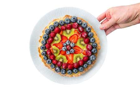 Hand carries homemade shortcrust pastry cake with mixed berries, raspberries, strawberries and...