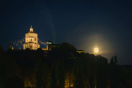 Turin, Italy. Night view of the Church of Santa Maria al Monte dei Cappuccini with the rising full moon on the right. July 13, 2022.の写真素材