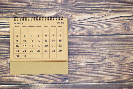 Top view of new year calendar January 2023 of yellow straw color on old wooden background with...
