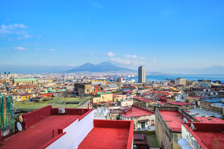Naples, Italy. View of the city from above, from Corso Vittorio Emanuele street. In the distance Mount Vesuvius and the Port of Naples. In the foreground some building rooftops. 2023-01-03.のeditorial素材