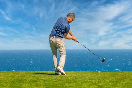 Golfer on a golf course with a beautiful view of the seaの写真素材