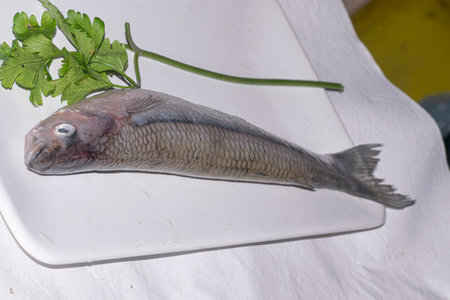 Herring fillet with parsley on a white chopping board.