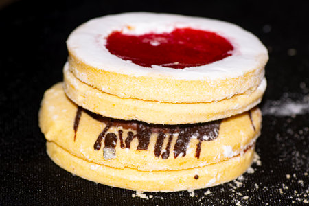 cookies with jam and icing sugar on a black background. macro