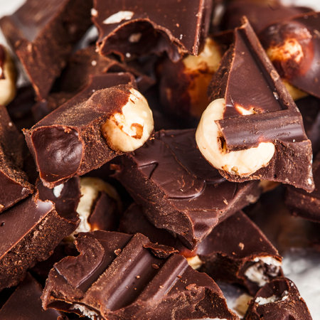 Crashed blach chocolate bar with large hazelnuts, isolated on white backgroundの写真素材