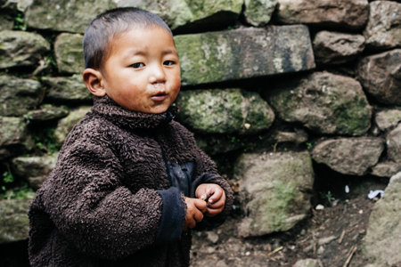 HIMALAYAS, EVEREST REGION, NEPAL - OCTOBER 20, 2018: Portrait nepalese small boy near their house, on the street in Himalayan village, Nepalのeditorial素材