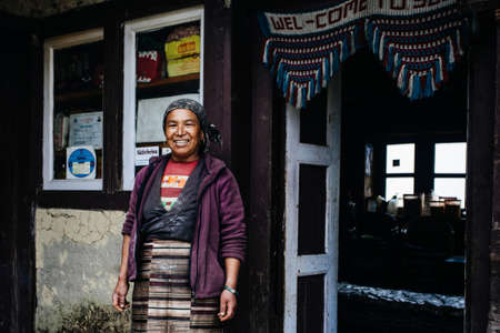 BUPSA, NEPAL - CIRCA OCTOBER 2018: Nepalese woman near her house, and lodge, circa October 2018 in...