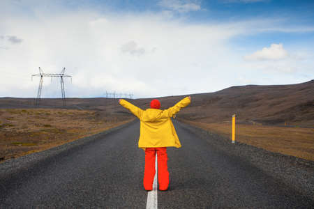 Happy tourist woman in bright clothes and yellow coat, enjoying traveling Icelandの写真素材