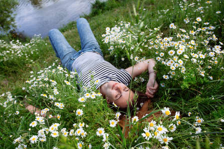 Beautiful young woman with brown hait, smiling, in chamomile fieldの写真素材