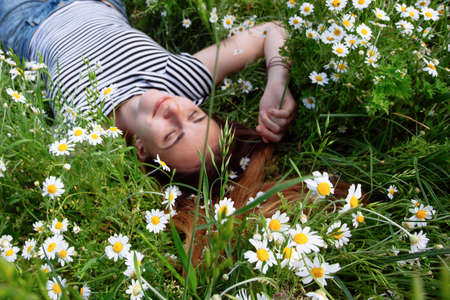 Beautiful young woman with brown hait, smiling, in chamomile fieldの写真素材