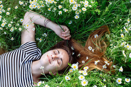 Beautiful young woman with brown hait, smiling, in chamomile fieldの写真素材