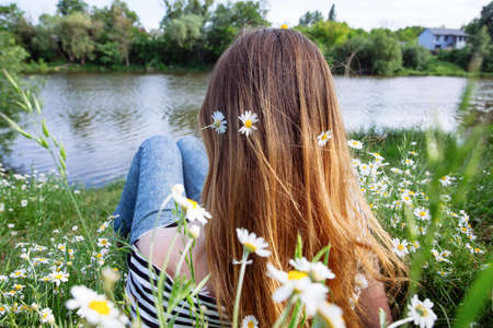 Beautiful young woman with brown hait, smiling, in chamomile fieldの写真素材