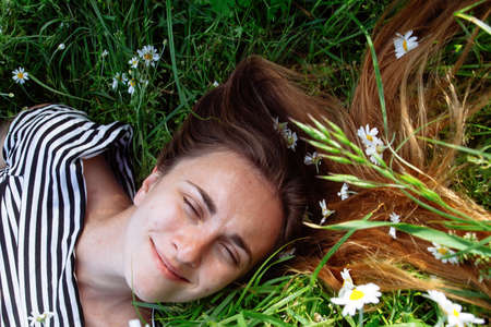 Beautiful young woman with brown hait, smiling, in chamomile field