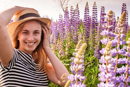 Beautiful young woman in hat in lupine fieldの写真素材