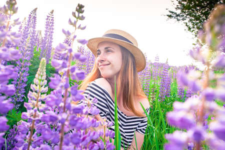 Beautiful young woman in hat in lupine fieldの写真素材