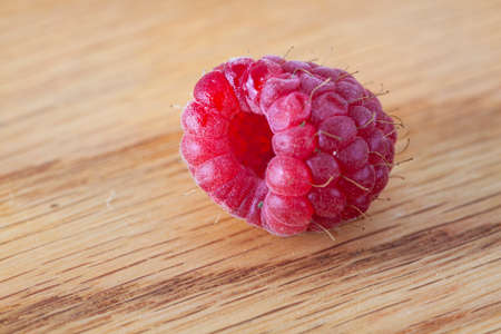 Bright crimson raspberry on the wooden backgriund