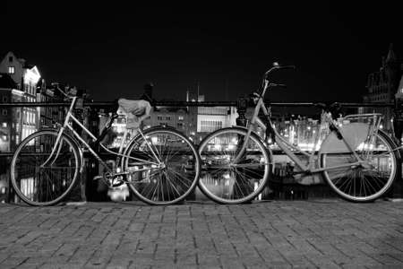 Night city view of Amsterdam canal, bridge, boats and bicycles, Holland, Netherlands.の写真素材
