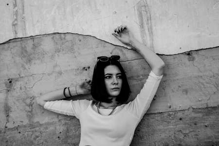 Lonely woman leaning against concrete wall in urban environment.の写真素材