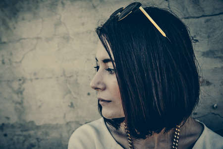 Lonely woman leaning against concrete wall in urban environment.の写真素材
