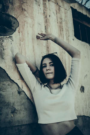 Lonely woman leaning against concrete wall in urban environment.の写真素材