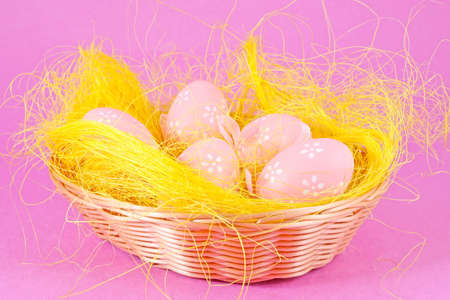 Pink eggs in the basket isolated on lilac